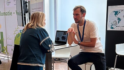 People are gathered at an information booth, talking.