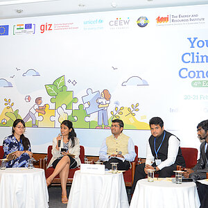 7 junge Menschen sitzen auf einem Diskussionspanel der Youth Climate Conclave 2023
