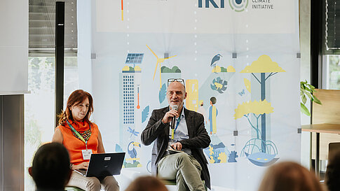 Two people in conversation, audience in the foreground.