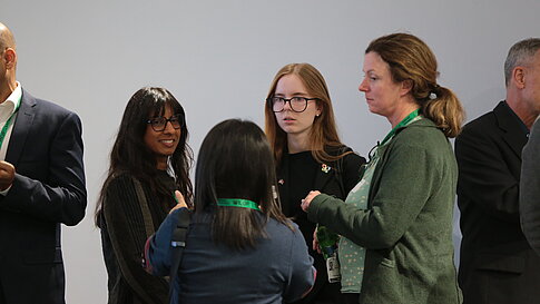 Group of people wearing name tags talking in front of a white wall