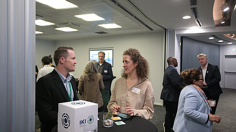 Several people are talking at high tables in a modern, well-lit room