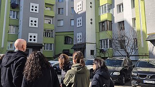 Menschen stehen vor einem Hochhauskomplex