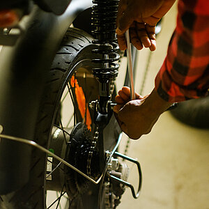 Eine Hand mit Schraubenschlüssel arbeitet am Hinterrad eines Elektro-Lastenrades.