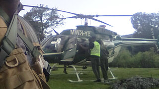 Helicopter on grassy field and a person in safety vest