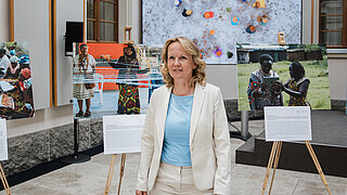 Bundesumweltministerin Steffi Lemke steht vor 3 großformatigen Fotos, die auf Staffeleien liegen.