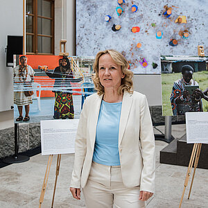 Bundesumweltministerin Steffi Lemke steht vor 3 großformatigen Fotos, die auf Staffeleien liegen.t