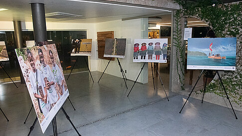 Foto der Ausstellung des IKI‑Fotowettbewerbs. Schwarze Staffeleien stellen großformatige Drucke der Gewinnerbilder aus. Die Anordnung wirkt wie eine kleine Galerie.