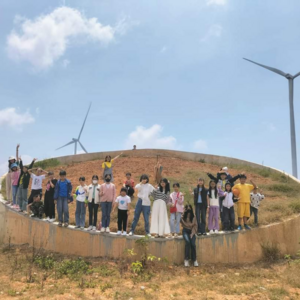Eine Gruppe von JUgendlichen steht in Vietnam im Kreis unter blauem Himmel und einem Windrad.