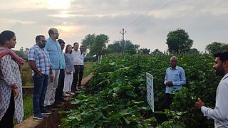 Sechs Beteilgte des Projektes RECAP4NDC stehen am Rande eines Feldes in Alwar, Rajasthan, und lassen sich von Landwirten die Landnutzung beschreiben.