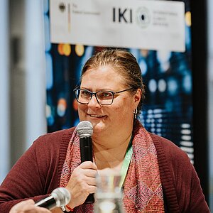 Andrea Kämpf, Leiterin der Geschäftsstelle des Unabhängigen Beschwerdemechanismus der IKI, spricht auf einer Veranstaltung auf der Bühne in ein Mikrofon.
