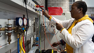 Technikerin an einer Lehrbank mit bunten Kabeln