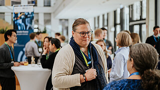 Andrea Kämpf im Gespräch mit einer Frau bei einer IKI-Veranstaltung in Berlin mit zahlreichen Gästen.