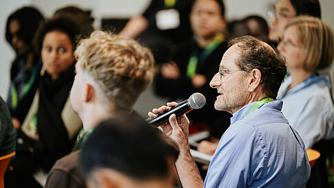 Audience member asking a question with a microphone.