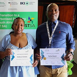 zwei Männer und eine Frau halten Urkunden in den Händen