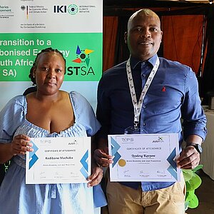Two men and a woman are holding documents in their hands