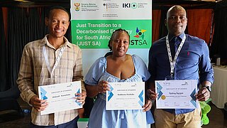 Two men and a woman are holding documents in their hands