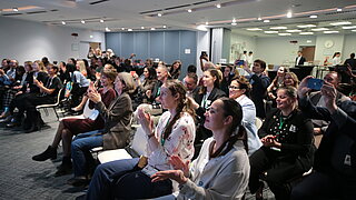 Audience sitting in rows in a conference room applauding