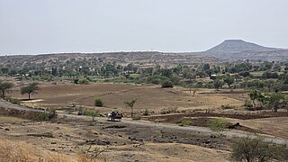 Eine weite, menschenleere und trockene Landschaft in im indischen Distrikt Dhule, Maharashtra, auf der Landwirtschafts- und Agroforstmaßnahmen umgesetzt werden sollen.