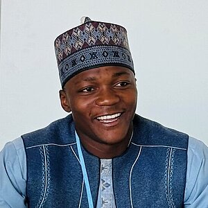 A young man sits at a conference table.