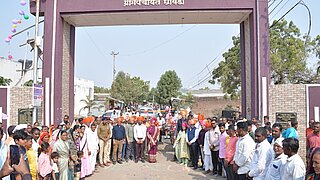 Eine große Gruppe von Menschen, darunter Landwirte stehen in Dhule, Maharashtra, im Halbkreis angeordnet..