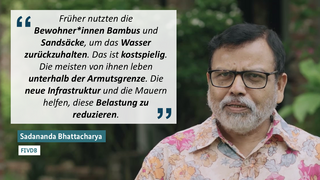 Sadananda Bhattacharya, in einem rosafarbenen Blumenhemd und mit Brille, äußert sich zu den Herausforderungen armer Einwohner beim Schutz vor Überschwemmungen; sein Zitat ist im Bild eingeblendet.