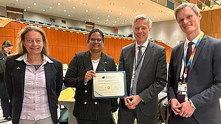 Vier Personen, zwei Männer und zwei Frauen, bei einer Preisverleihung. 