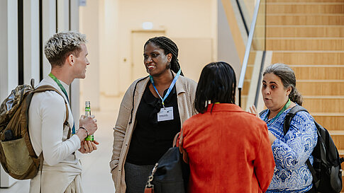 Small group in conversation in front of stairs.