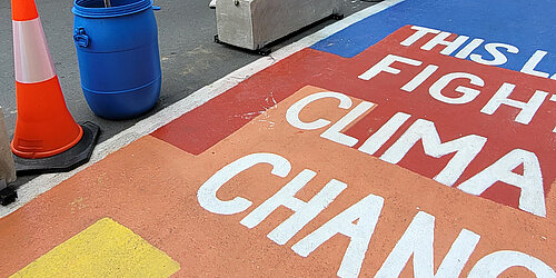 A cycle path painted in bright colours with the words "This lane fights climate change" on it.