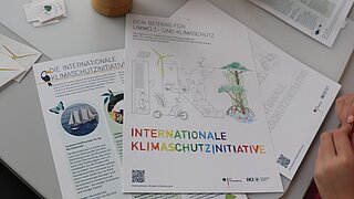 Ein Malbogen mit einem Umweltschutz- und Klimaschutz-Thema, das von einem Kind ausgemalt wurde. Auf dem Papier sind auch Sticker von verschiedenen umweltfreundlichen Symbolen zu sehen