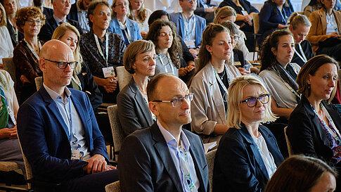 Gruppe von Menschen in einem Saal, die aufmerksam nach vorne schauen