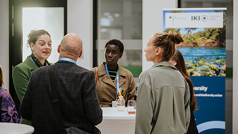 Participants talking at a standing table in the foyer.
