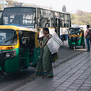 Eine Frau steigt mit ihrem Gepäck in ein Tuktuk in Indien