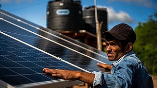 Ein Mann in Bolivien arbeitet an einem stehenden Solarmodul.