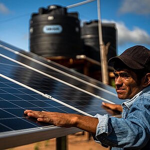 Ein Mann in Bolivien arbeitet an einem stehenden Solarmodul.