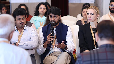 At an event: A man in the audience is holding a microphone and giving a speech.