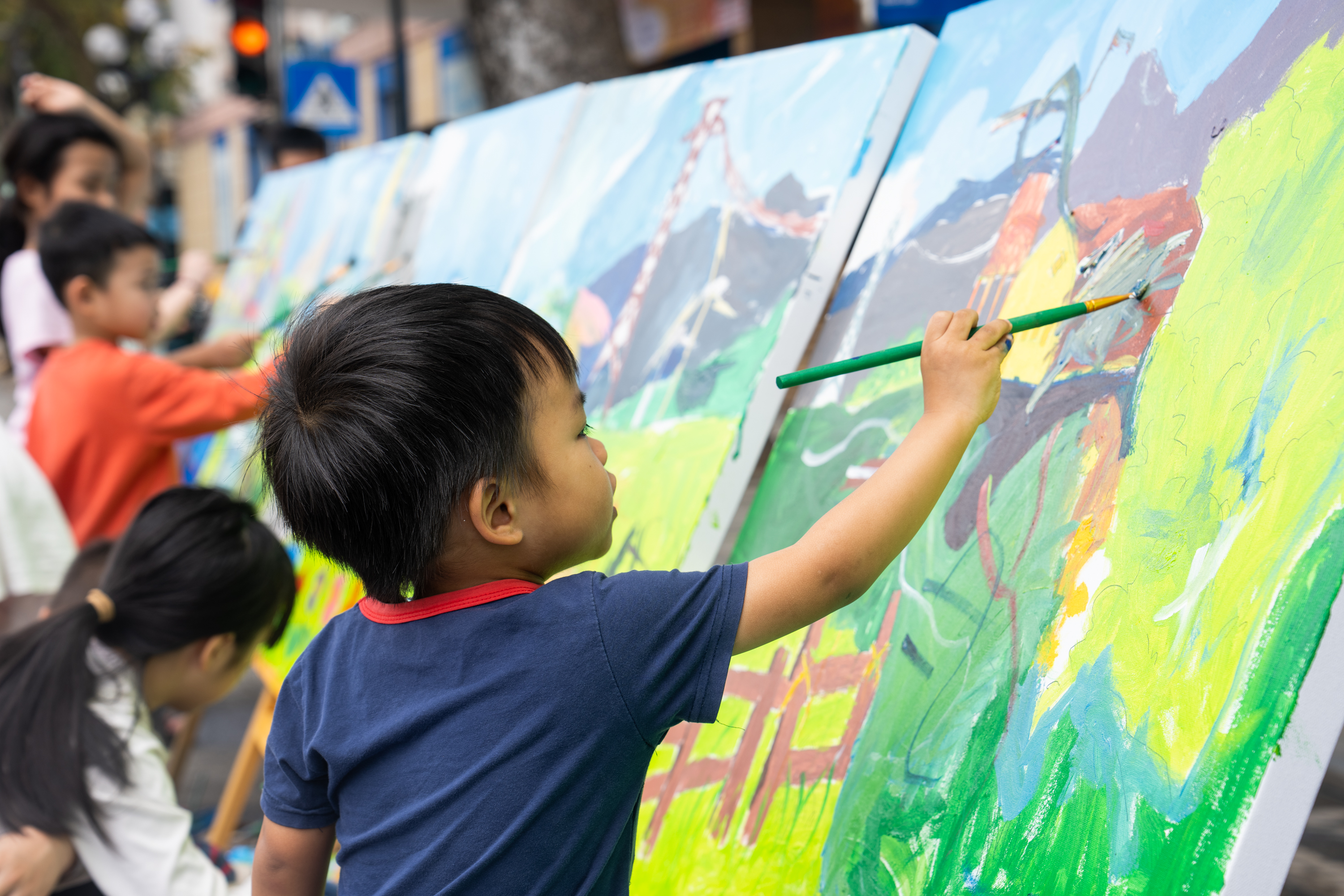 A child painting a on a large canvas. 