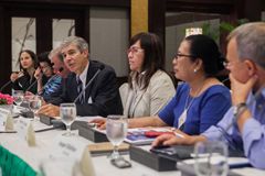 Mehrere Personen sitzen an einem Tisch mit Mikrofonen