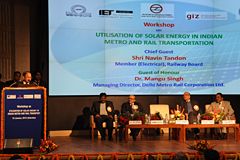 1 Mann steht am Rednerpult, 4 Männer sitzen auf Podium