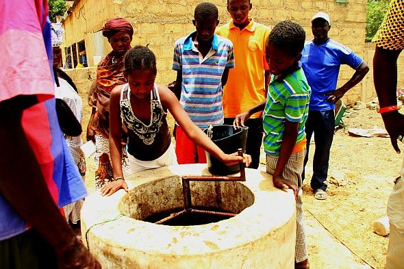 Frauen drehen Kuhdung mit Kurbel