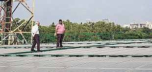 zwei Männer stehen auf Dach und betrachten Solaranlage