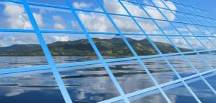 Zwei Arbeiter mit Schutzhelömen stehen auf einer Solardachanlage und säubern sie mit Wasser und Wischer.