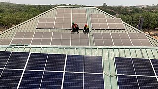 Zwei Personen installieren Solarmodule auf einem Dach