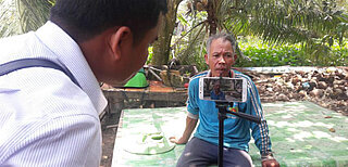 Bürgerjournalist interviewt einen Mann mit seinem Smartphone.