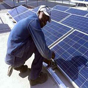 Person kneeling next to solar panels